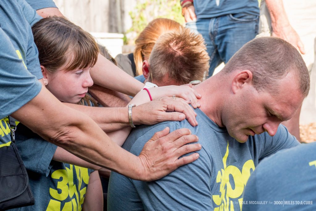 Friends and family pray over Rob DeCou to ask for strength, safety and perseverance before the Race Across America starts Tuesday.